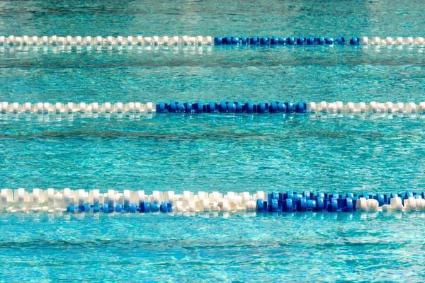Blue and white lane ropes across clear turquoise pool water.